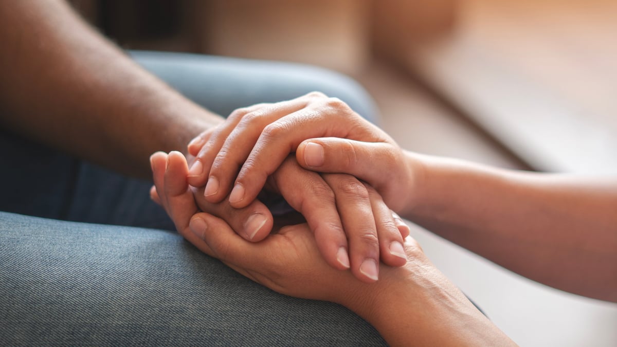 Dos personas tomándose de la mano en gesto de consuelo
